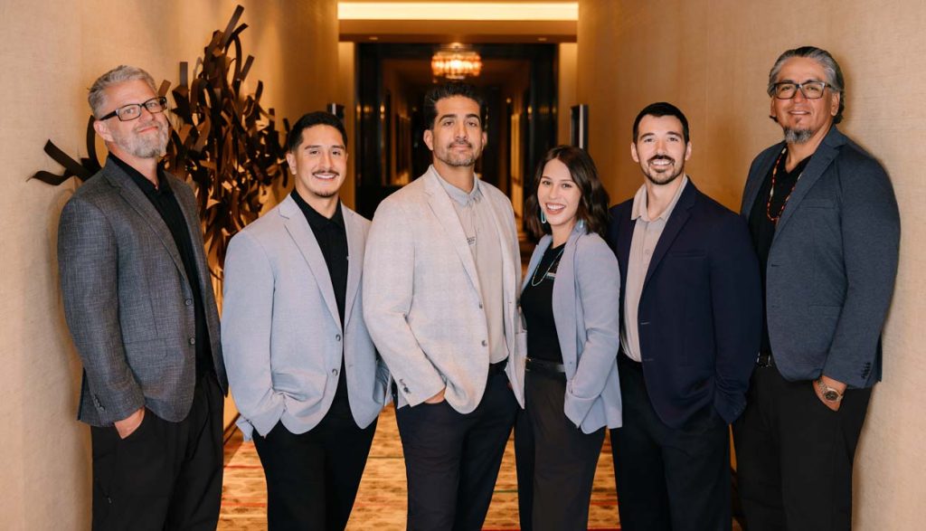 Sovereignty Construction leadership team of six in business attire posing together in a hotel hallway, representing the firm's Native-owned leadership serving Tribal Nations.