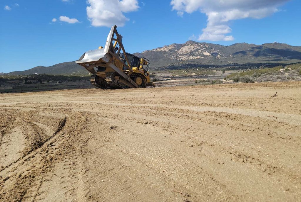 Bulldozer working on a dirt site with mountains in the background, Sovereignty Construction land development.